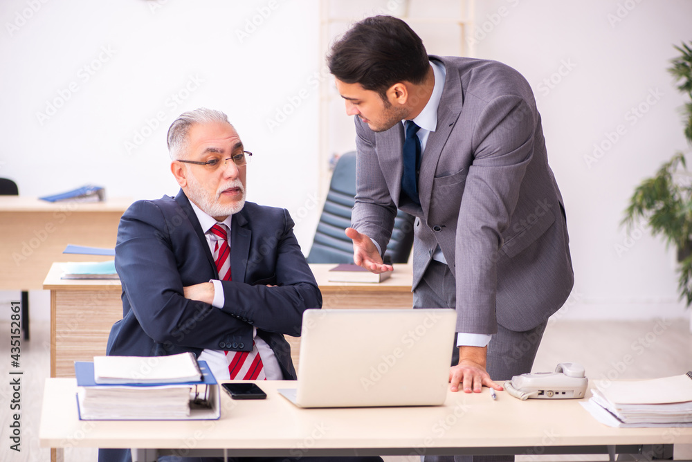 Old boss and young male employee working in the office