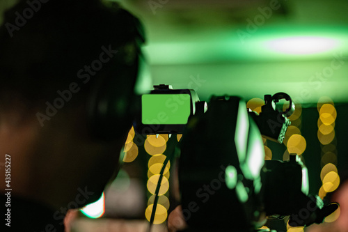 Silhouette of film maker with chroma in camera viewfinder. Soft image with bokeh background.