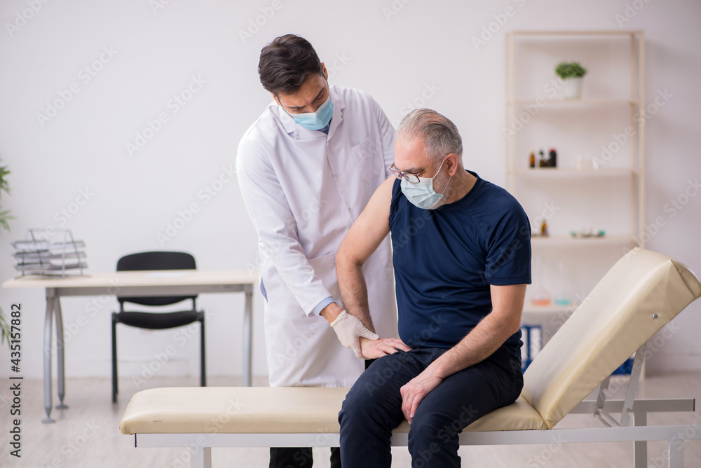 Fototapeta premium Old male patient visiting young male doctor in vaccination conce