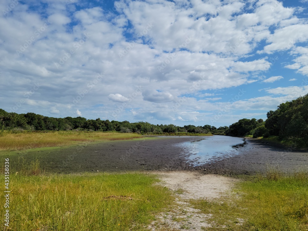 Dried river bank with scattered white clouds