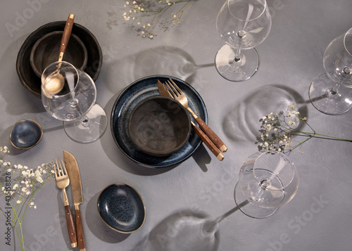 Table setting with a black and blue plates on gray background. Minimalism concept.