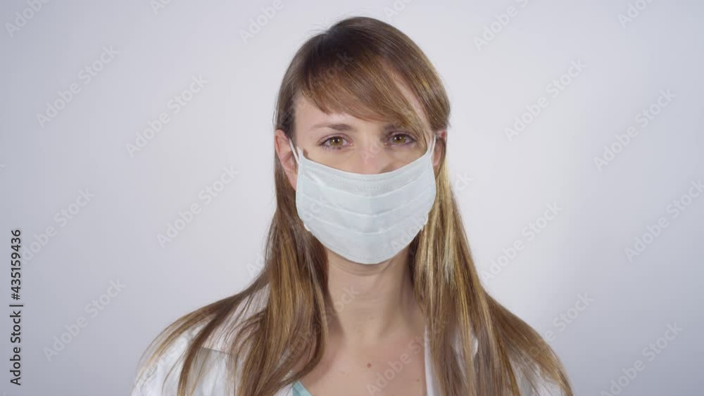 CLOSE UP: Content Caucasian female doctor puts on a facemask to protect herself during coronavirus outbreak. Smiling nurse puts on a takes off a surgical mask while working in a covid 19 laboratory. CLOSE UP: Content Caucasian female doctor puts on a facemask to protect herself during coronavirus outbreak. Smiling nurse puts on a takes off a surgical mask while working in a covid 19 laboratory.