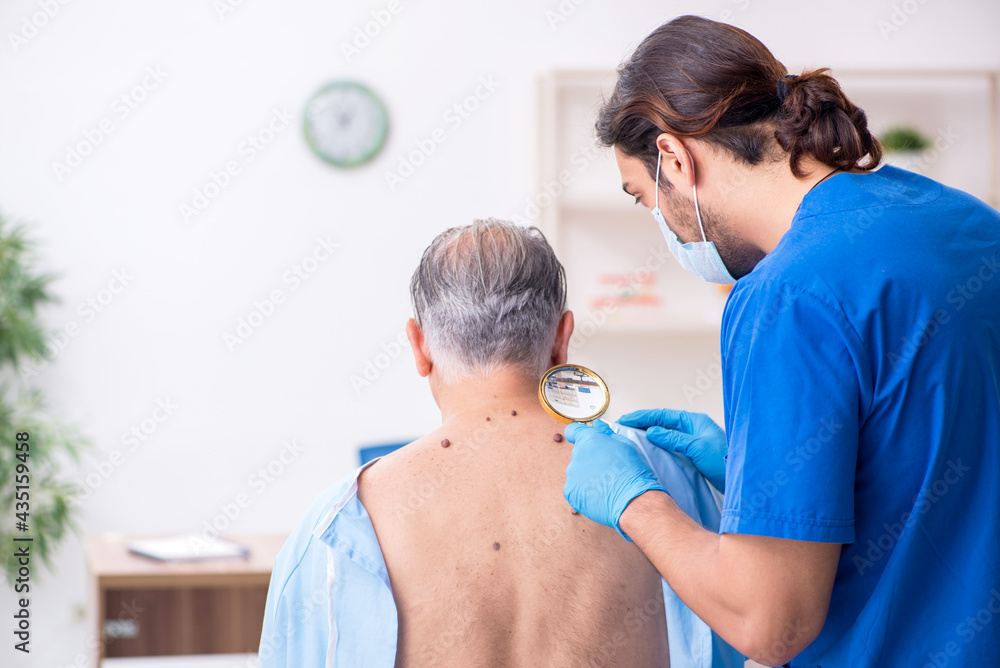 Obraz premium Old man visiting young male doctor dermatologist