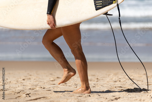 Australian Woman surfer walking along the Beach whit her Surfboard. Water Deport Concept
