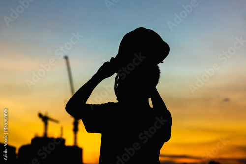 The engineer boy silhouette looks at the future building beautiful in the sunset  © Treecha