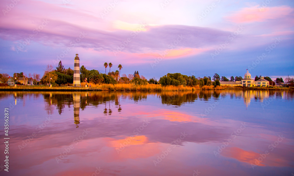 lighthouse at sunset, blue pink magnificent nature sky reflection on the water