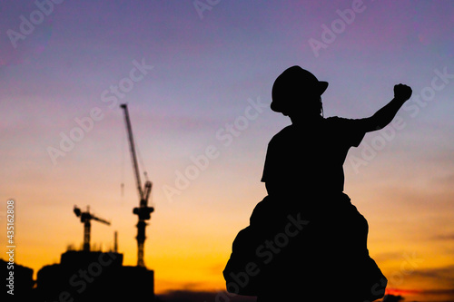 The silhouette of the happy father and son wearing a construction helmet holding hands expressing the joy of the sunset