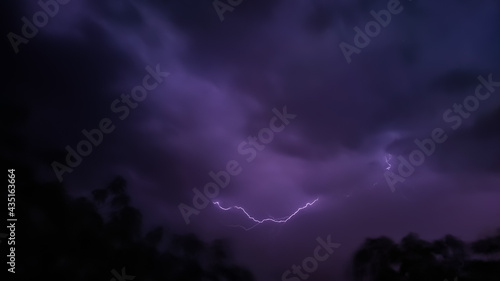 Lightning bolt between black clouds at night, amazing and dramatic view