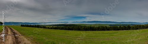 Panoramic landscape, dirt road leading through the green meadow on the top of the muntain in Romania.
