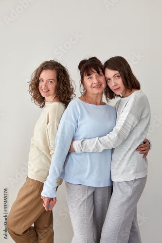 Smiling mother hugging daughters and looking at camera