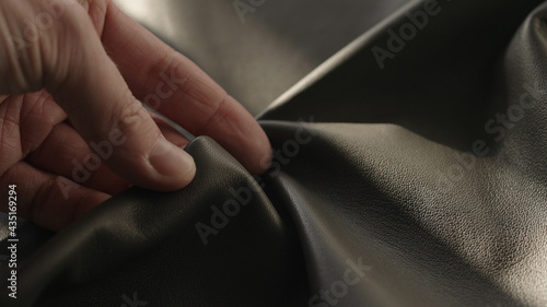 Foto Man hand touching soft leather with sun shining from a window