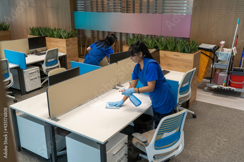 Cleaning ladies clean desks in an empty office space.Cleaning maintenance concept