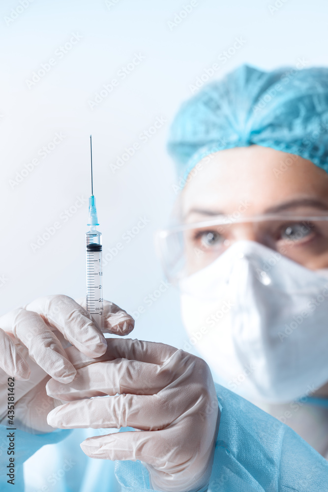Close up view of doctor with the syringe of covid vaccine on blue back Close up view of doctor with the syringe of covid vaccine on blue back