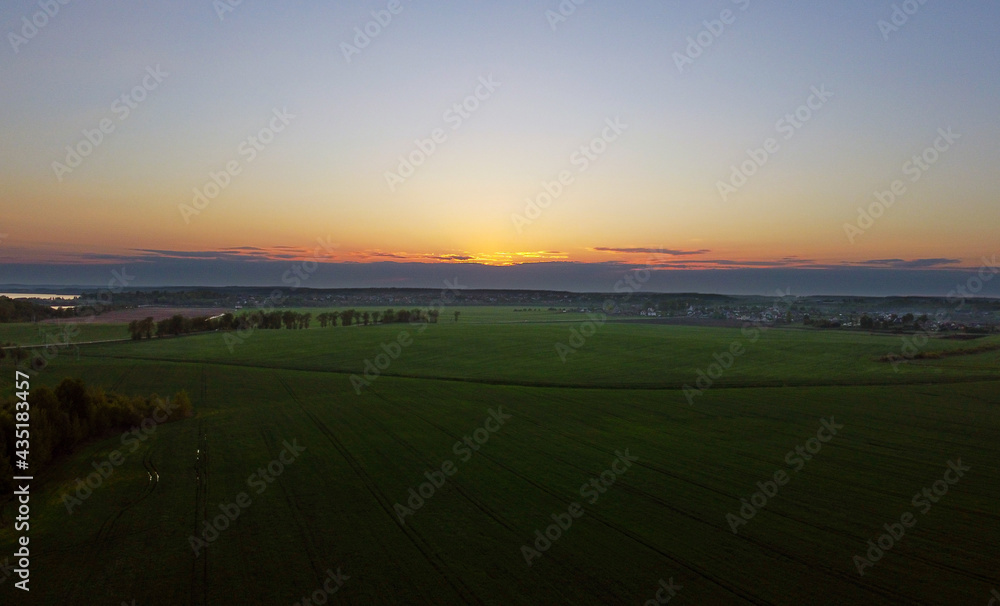 Fototapeta premium Drone view of the evening landscape at sunset with fields and clouds