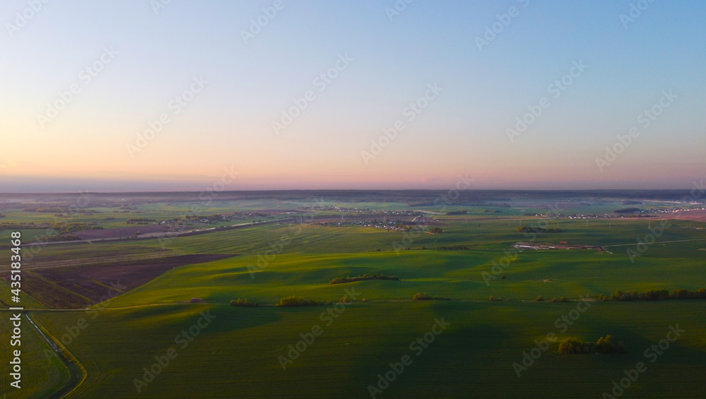 Drone view of the evening landscape at sunset with fields and clouds