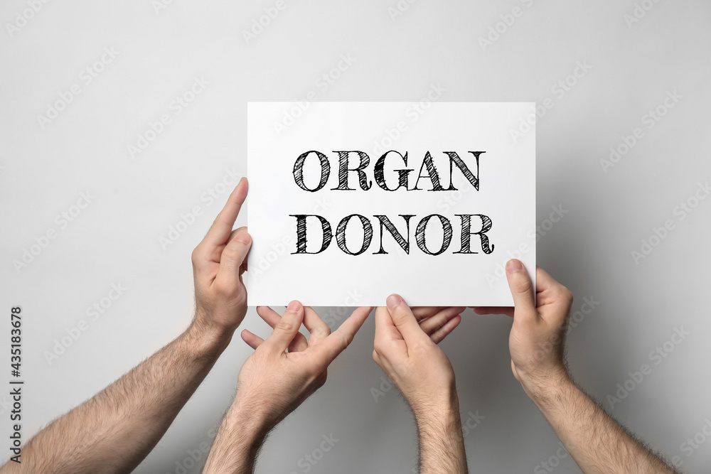 Men holding card with text ORGAN DONOR on light background, closeup Men holding card with text ORGAN DONOR on light background, closeup