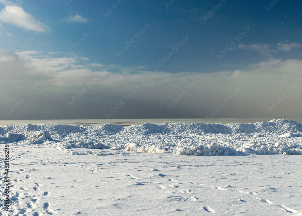 winter landscape by the sea, snowy pieces of ice by the sea, dunes covered with a white layer of shining snow