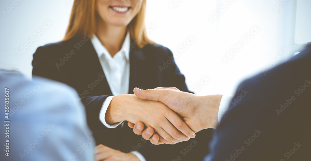 Businesspeople or lawyers shaking hands finishing up a meeting in blue toned office , close-up. Success at negotiation and handshake concepts