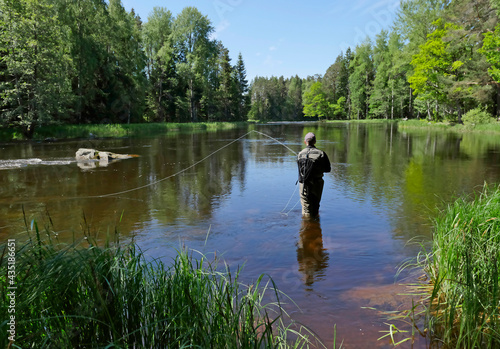 Fly fisherman using flyfishing rod in a beautiful river in spring photo