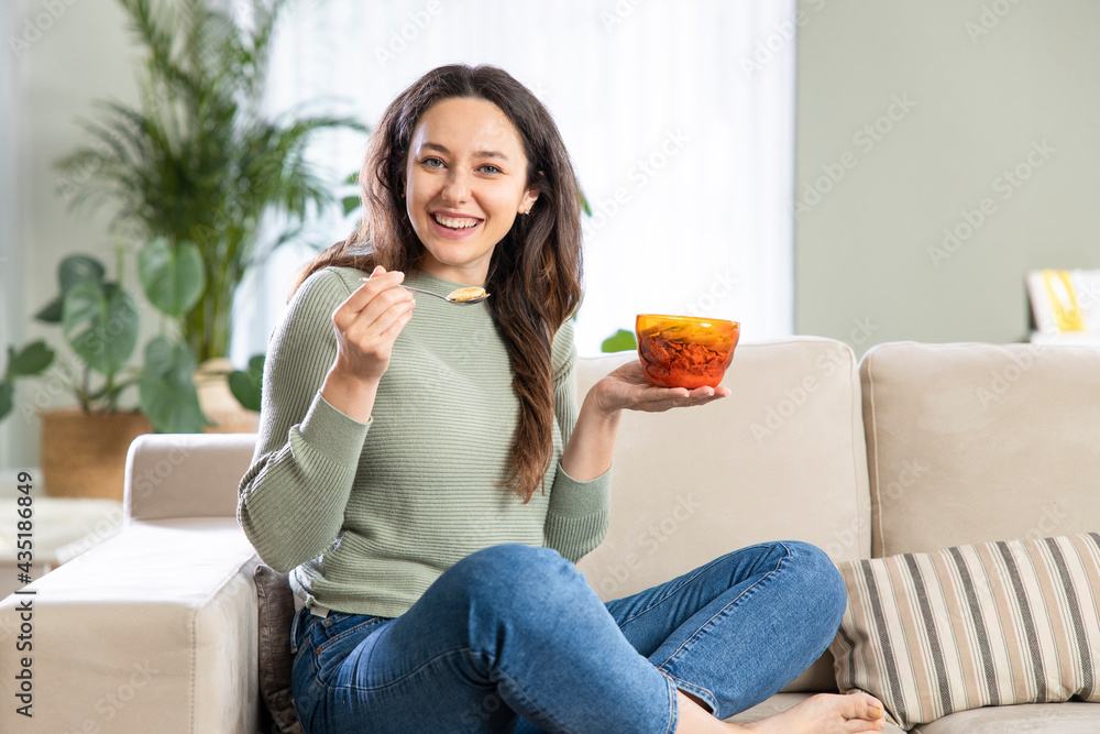 Young woman eating healthy breakfast in livingroom.