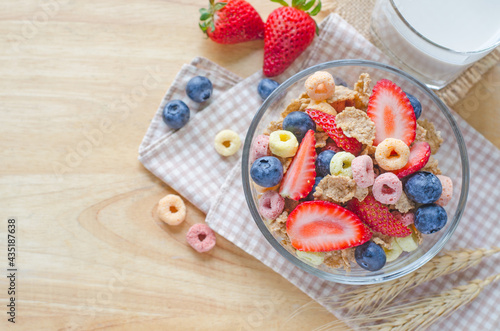 Cereal food with fresh strawberry and blueberry fruit and milk on wooden table background with copy space for adding text, for healthy breakfast meal concept