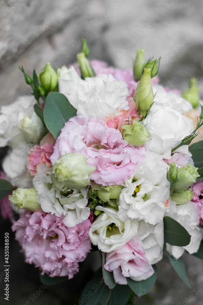Beautiful bridal bouquet of white and pink flowers and greenery, on a gray textural background. Copy space. Lisianthus wedding bouquet.