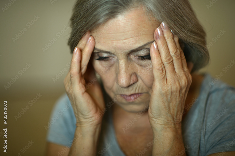 Portrait of sad senior woman with headache