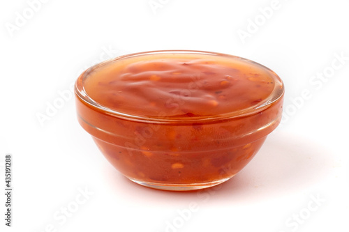 Hot pepper sauce or ketchup with seeds in a transparent bowl isolated on a white background.
