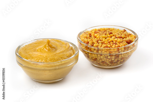 Mustard yellow sauce in a clear bowl and Pickled mustard seeds isolated on a white background.