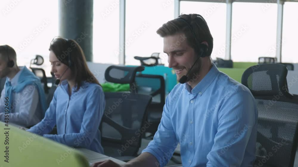 Call center worker accompanied by his team. Smiling customer support operator at work. Call center worker accompanied by his team. Smiling customer support operator at work.