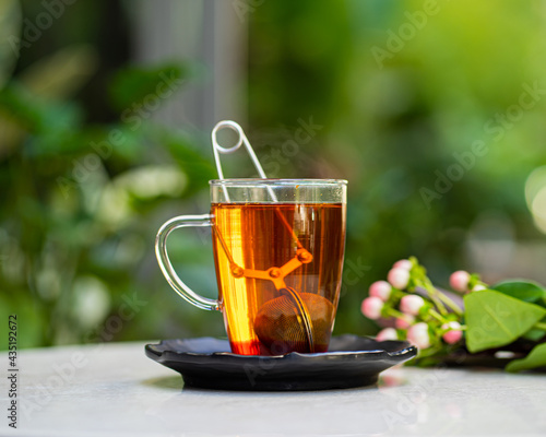 cup of fresh aromatic tea on table with nature flowers background