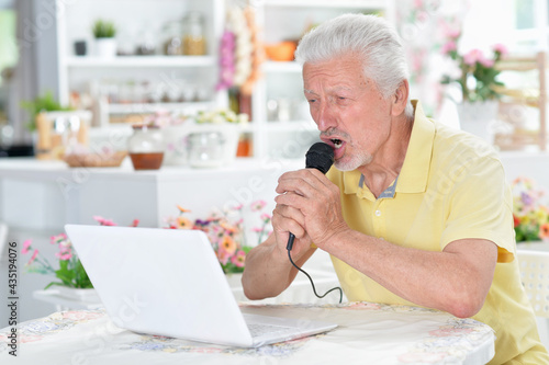 Emotional senior man singing karaoke with tablet