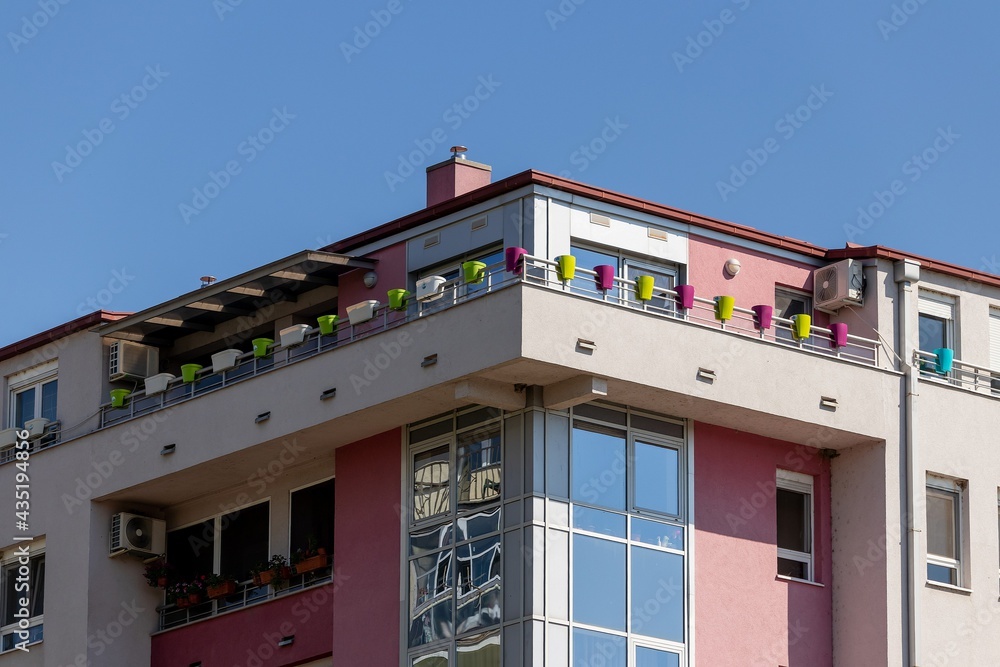 Multicolored plastic flower pots set for planting flowers on top floor balcony of modern apartment building