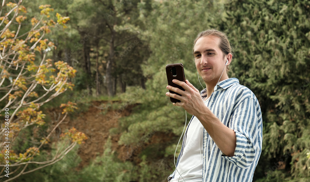 Man holding phone looking at screen watching social media video content outdoors Man holding phone looking at screen watching social media video content outdoors