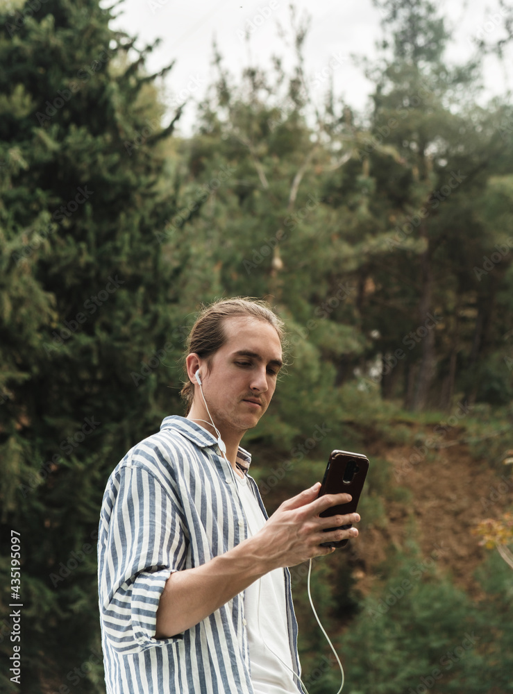 Man holding phone looking at screen watching social media video content outdoors Man holding phone looking at screen watching social media video content outdoors