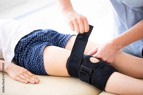 closeup of Physician putting black ortosis on kid's knee