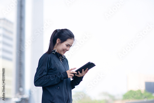 Woman look smile and happy with black sportswear holding and touch at tablet. Outdoor working concept. communications and lifestyle concept.