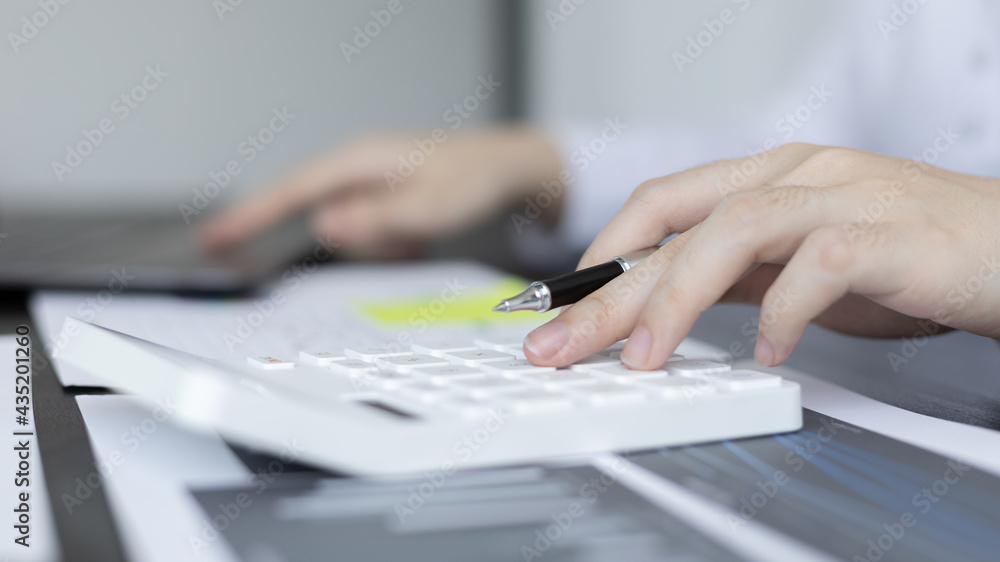 Young Asian businesswoman presses a calculator to calculate income tax and corporate income in a private office, Finance, Accounting, Tex, Statistical graphs of marketers investing in real estate. Young Asian businesswoman presses a calculator to calculate income tax and corporate income in a private office, Finance, Accounting, Tex, Statistical graphs of marketers investing in real estate.