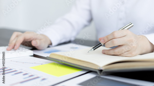 Head of accounting is recording the company's financial growth statistics using graphs as a reference for reviewing and analyzing the results, Taking notes and analyzing data graphs in office.