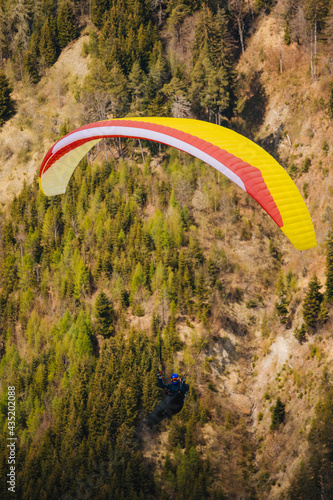 Paragliding. The paragliding wing flies against the background of a spring landscape in the alps.