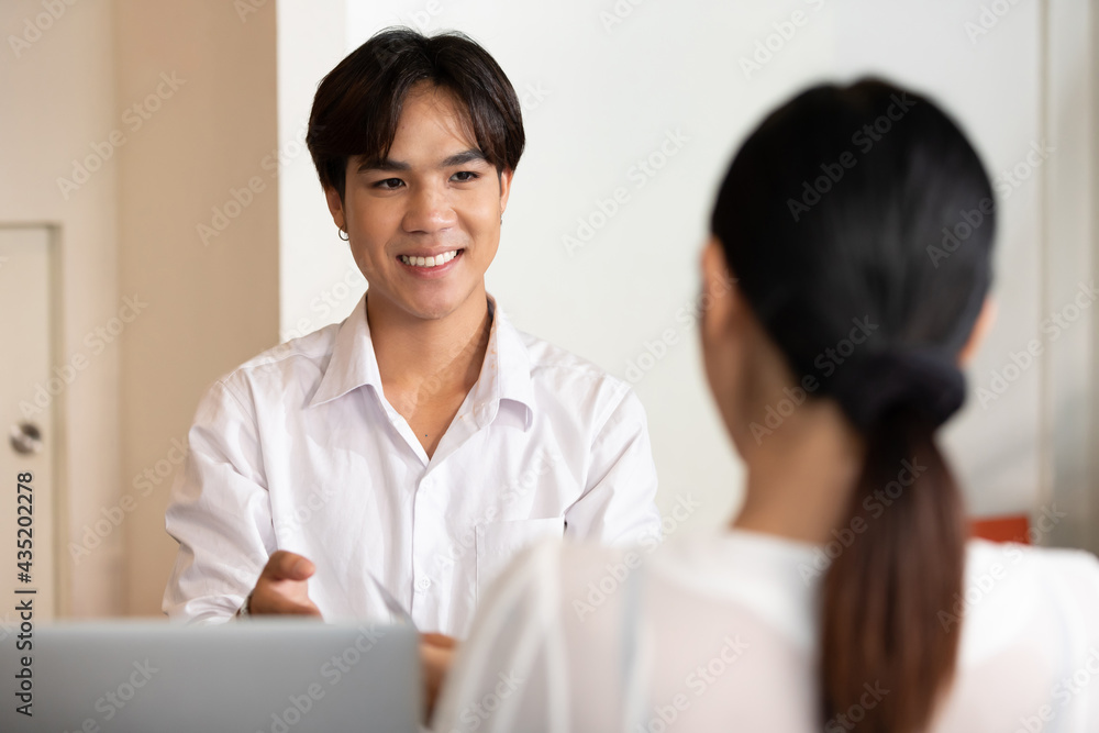male receptionist or hotel front desk smiling and receiving credit card from woman guest male receptionist or hotel front desk smiling and receiving credit card from woman guest
