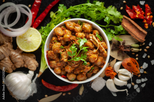 Photography Chickpeas masala (Spicy chola or chhole curry)  garnished with fresh green coriander and ingredients