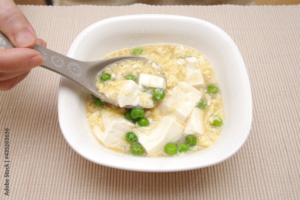 豆腐と溶き卵の甘煮を食べている 豆腐と溶き卵の甘煮を食べている