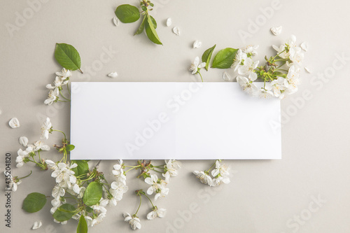 Elegant floral composition with paper blank in the centre of gray background. Branding mock up, holiday marketing concept.