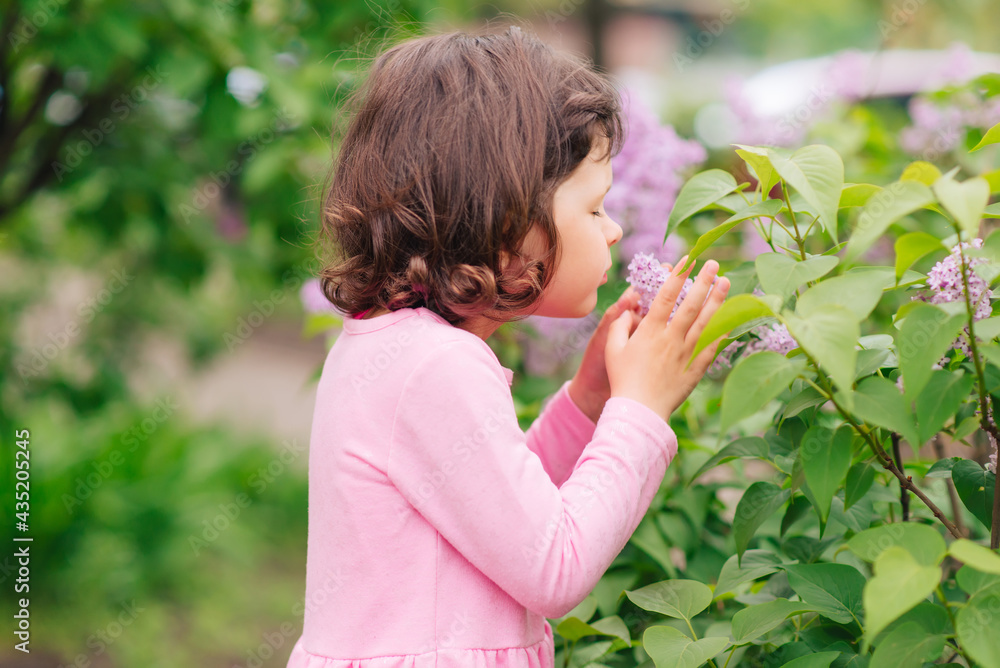girl sniffs flowers in the garden on a summer sunny day girl sniffs flowers in the garden on a summer sunny day