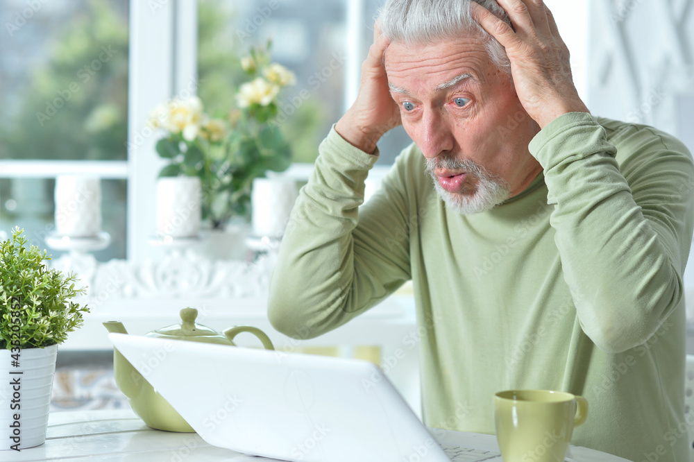 Emotional senior man using laptop Emotional senior man using laptop