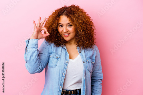 Young latin curvy woman isolated on pink background cheerful and confident showing ok gesture.