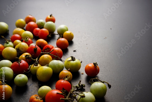 Cherry tomatoes flat lay on black grunge texture abstract background. Food, vegetables photography. Head on, horizontal, neutral vintage moody image style.