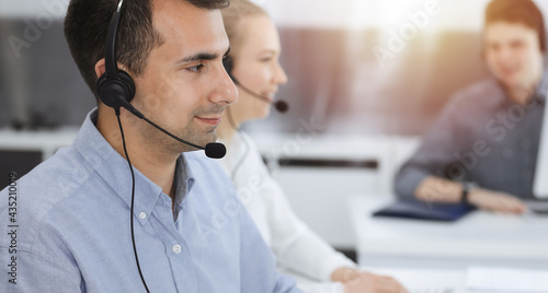 Call center. Group of casual dressed operators at work. Adult businessman in headset at customer service office. Telesales in business