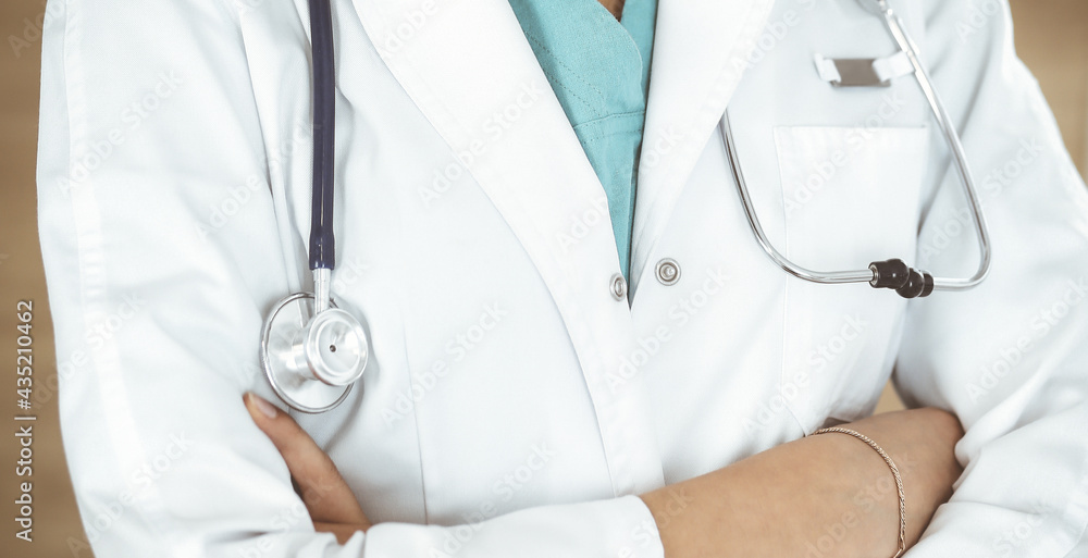 Unknown female doctor standing with arms crossed in clinic, close-up. Medicine concept Unknown female doctor standing with arms crossed in clinic, close-up. Medicine concept